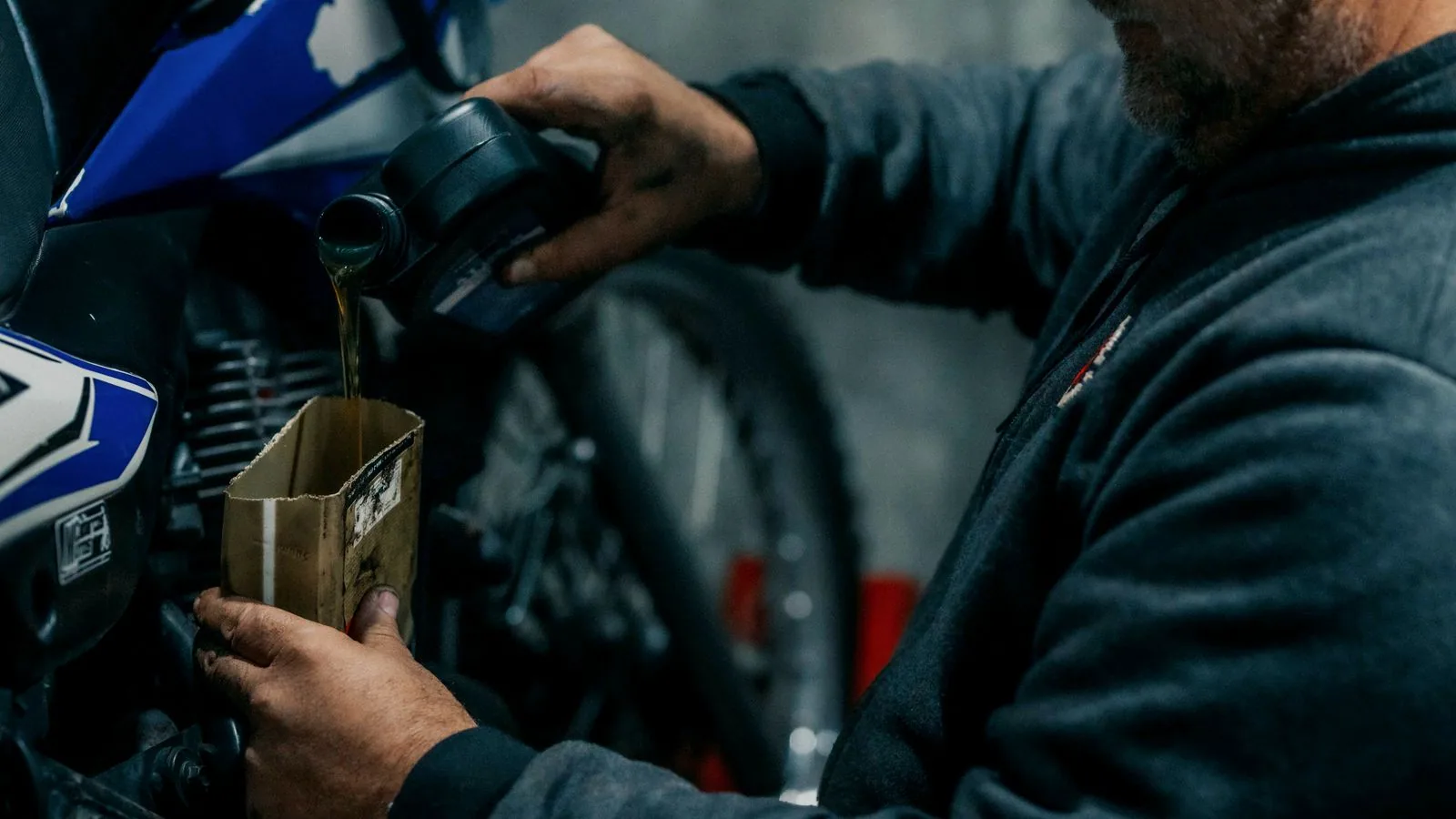 Photographie : un bidon d'huile de vidange et un bac de récupération posés au sol d'un garage