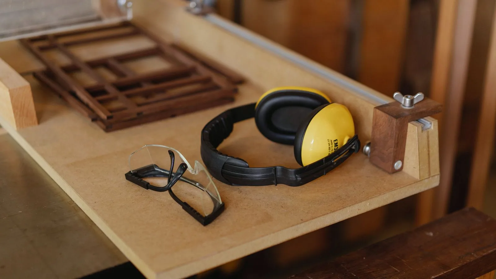 Photographie : des lunettes de protection, un casque antibruit et des gants posés sur un établi